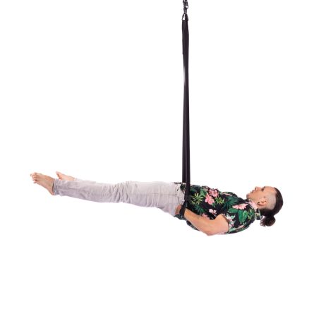 A performer in casual clothes hangs horizontally from aerial straps with his hands in his back pocket.