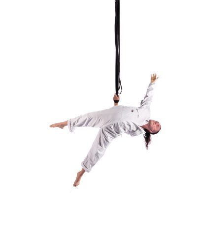 A performer in a white boiler suit hangs from one arm that is behind his back.